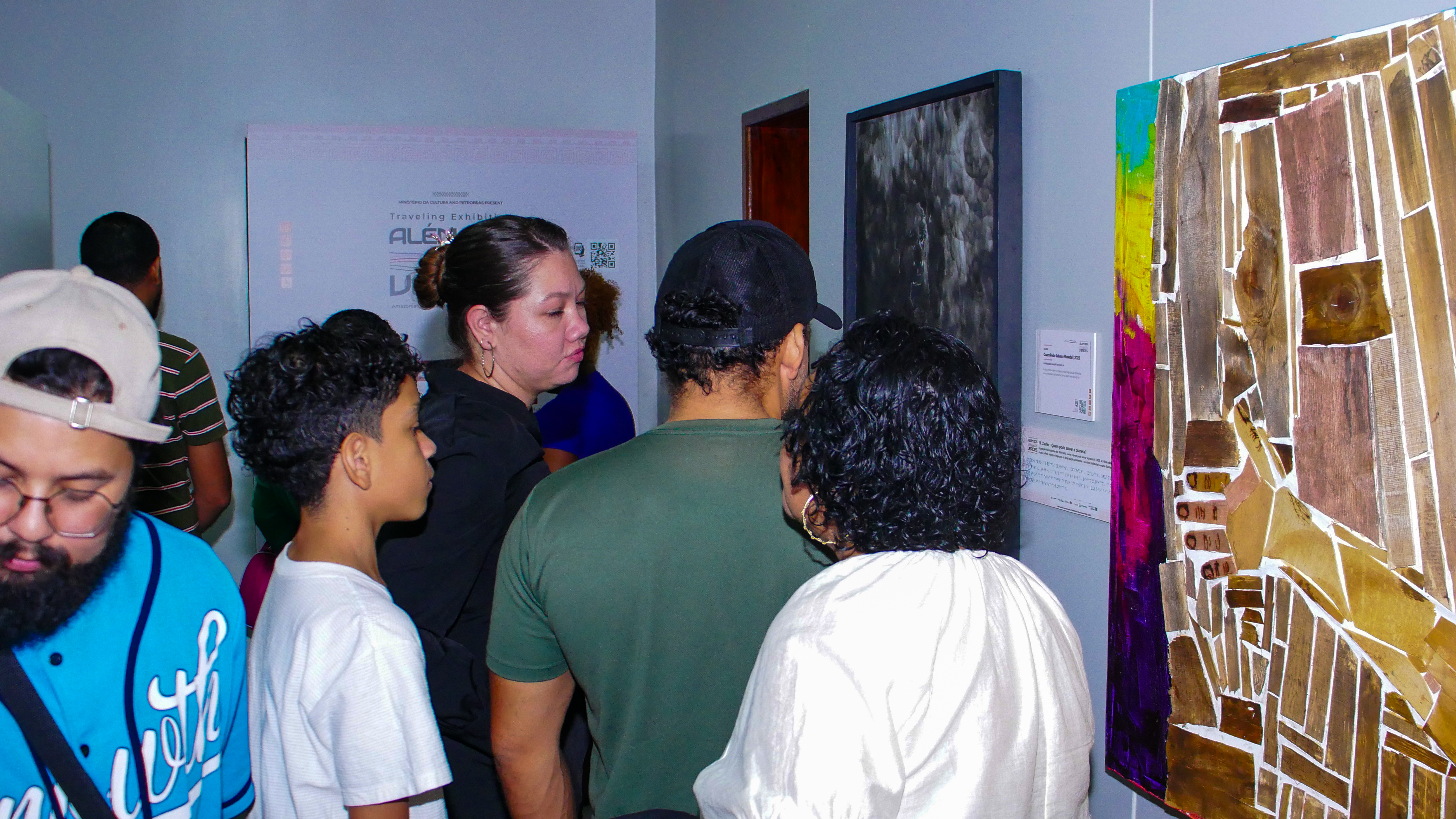 Exposição Além dos Verdes — família observando obras em madeira